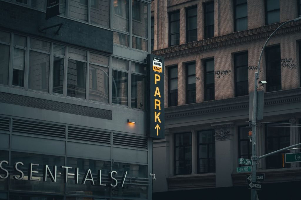 Moody street view of New York City buildings with parking and street signs. Urban atmosphere.
